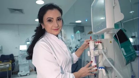 Valquíria Arenas de jaleco branco ajustando uma máquina de hemodiálise numa unidade de diálise